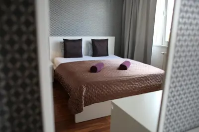 a bedroom with a bed with purple slippers on it at Golden Family Apartments in Prague