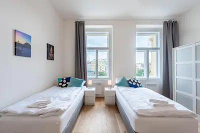 two beds in a room with two windows at Residence Tesnov Apartment in Prague