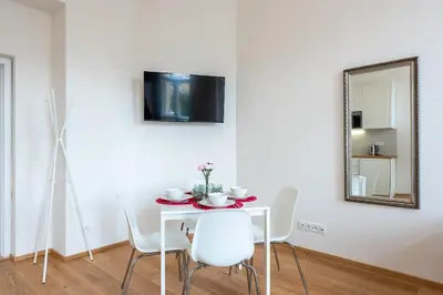 a white table with white chairs and a mirror at Residence Tesnov Apartment in Prague