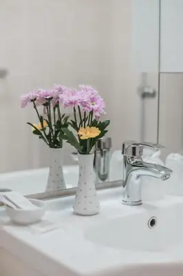 two vases with flowers sitting on a bathroom sink at Hotel Peko in Prague