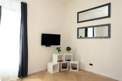a white living room with a tv and a mirror at The Apartment House - Mezibranska in Prague