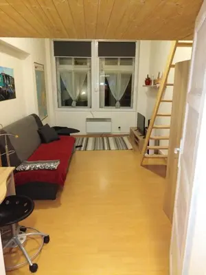 a living room with a red couch and a staircase at Studio Husitská 114/74 in Prague