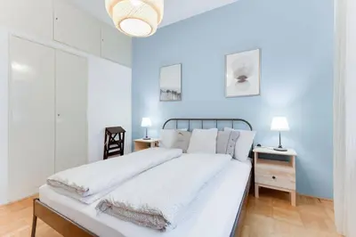 a white bedroom with a large bed and two tables at Apartment Alex in Prague