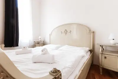 a white bed with two towels on top of it at Prague Days - Spacious Retro-vibes Apartment near Charles Square in Prague