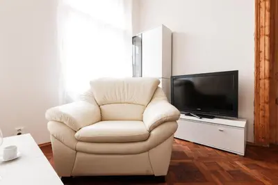 a white chair in a living room with a television at Prague Days - Spacious Retro-vibes Apartment near Charles Square in Prague