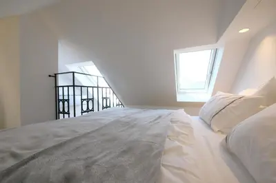 a white bed in a room with two windows at Prague Expat House in Prague