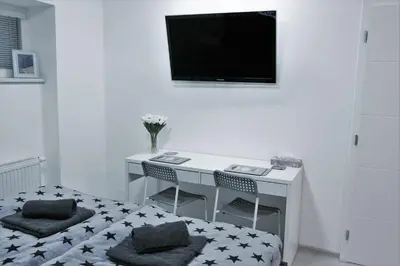 a white desk with two chairs and a television on a wall at Garden studio apt-FREE parking,close D8,metro,EXPO in Hovorčovice