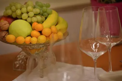 a bowl of fruit on a table with two wine glasses at Apartman Dalia Janáčkovo nábřeží in Prague