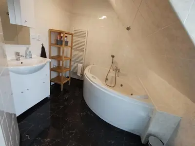 a bathroom with a white tub and a sink at Duplex with garden in Prague