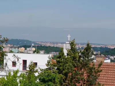 a white building with a cross in the distance at Duplex with garden in Prague