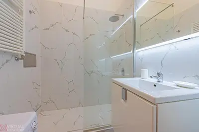 a white bathroom with a sink and a shower at Colorful Wenceslas square apartment in Prague