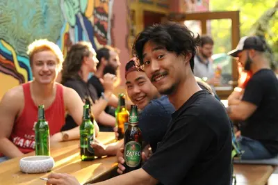 a group of people sitting at a bar with beer bottles at Hostel Elf in Prague
