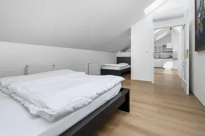 a white bedroom with a large white bed and wooden floors at Wellness Rooms Central in Prague
