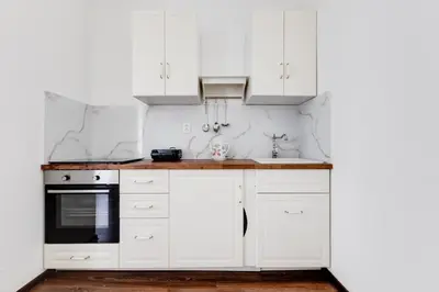 a white kitchen with white cabinets and a sink at Lovely Apartments Heart of Prague in Prague