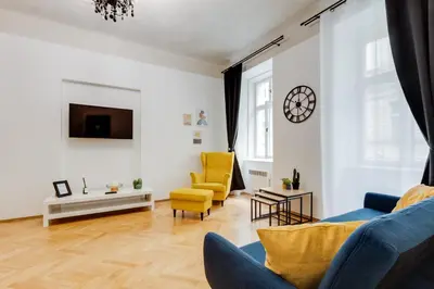 a living room with yellow chairs and a tv at Lovely Apartments Heart of Prague in Prague