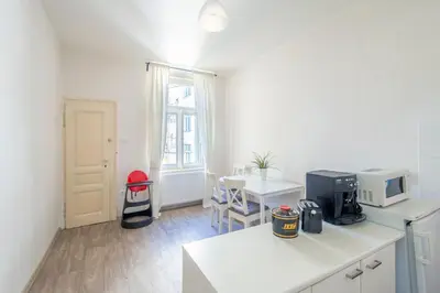 a white kitchen with a table and a microwave at TopApartmany in Prague