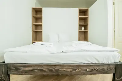 a bed with white sheets on a wooden platform in a room at Charles Bridge Hostel & Apartments in Prague
