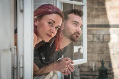 a man and a woman looking out of a window at Charles Bridge Hostel & Apartments in Prague