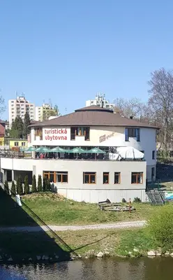 a white building next to a body of water at Hostel Příběh in Týnec nad Sázavou