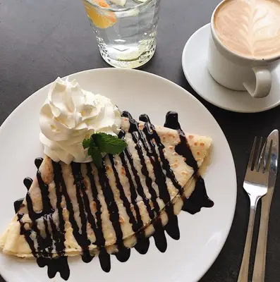 a piece of pie with whipped cream and a cup of coffee at Hostel Příběh in Týnec nad Sázavou