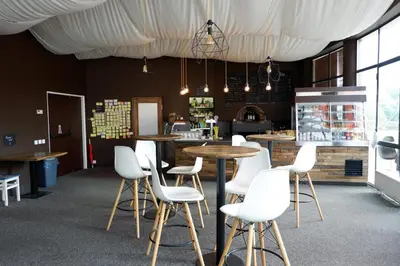 a restaurant with white chairs and tables and a counter at Hostel Příběh in Týnec nad Sázavou