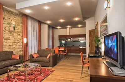 a living room with a couch and a tv and a kitchen at Residence Rybna in Prague