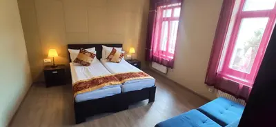a bedroom with a bed and a couch and two windows at Sun-House Pension - ParkingFree Limited spaces- in Prague