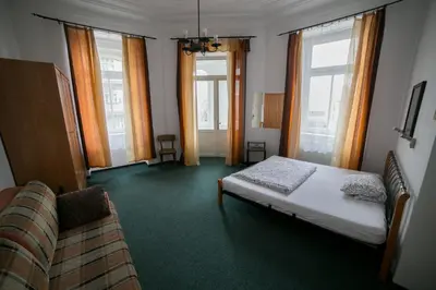 a bedroom with a bed and a couch and windows at Apartment Kahoun in Prague