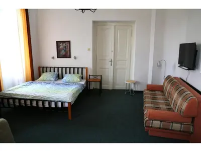 a bedroom with a bed and a couch and a tv at Apartment Kahoun in Prague