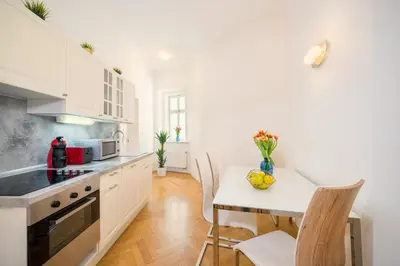 a kitchen with white cabinets and a table with a bowl of fruit at Old Town Square Premium Residence in Prague