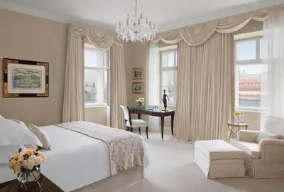 a bedroom with a bed and a desk and a chandelier at Four Seasons Hotel Prague in Prague