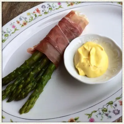 a plate with a wrapped asparagus and a bowl of mustard at Penzion V polích in Malé Číčovice
