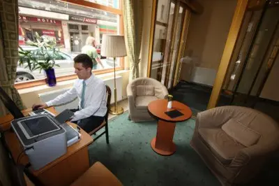 a man sitting at a desk with a computer in a room at Central Hotel Prague in Prague
