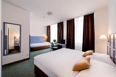 a hotel room with two beds and a mirror at Central Hotel Prague in Prague