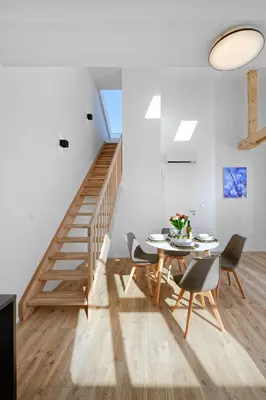 a dining room with a table and chairs and a staircase at DownTown Suites Jugoslavska in Prague