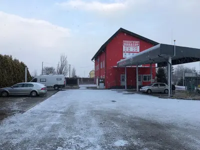 a red building with cars parked in front of a gas station at Motel Red Oil in Lovosice