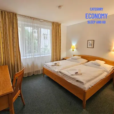 a bedroom with a bed and a desk and a window at Hotel Claris in Prague