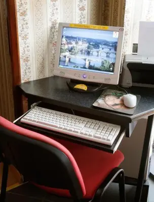 a computer monitor sitting on a desk with a red chair at Pension Lucie in Prague