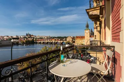a balcony with a table and views of the river at Bellevue Apartment in Prague
