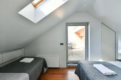a attic bedroom with two beds and a window at LUXURY CENTRAL DUPLEX WITH TERRACE in Prague