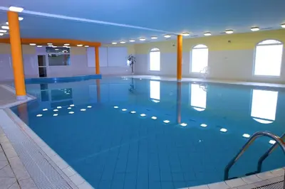 a large indoor swimming pool with blue tile floors at Hotel Floret in Pruhonice