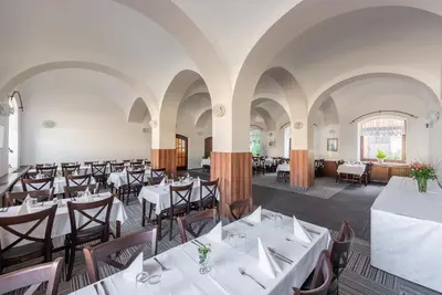 a dining room with white tables and chairs at Hotel Floret in Pruhonice