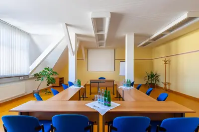 a classroom with wooden tables and blue chairs at Hotel Floret in Pruhonice