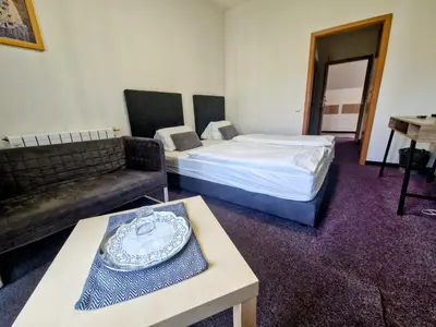 a room with two beds and a couch and a table at Family hotel Maxim in Beroun