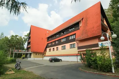 a building with an orange roof and a car parked in a parking lot at Hotel Laguna Slapy in Netvořice
