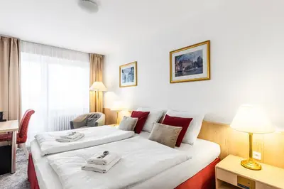 a hotel room with two beds and a desk at Hotel Oáza Praha in Prague