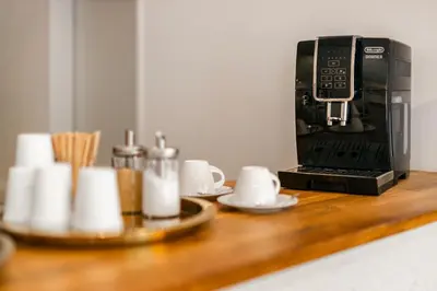 a coffee maker on a counter with cups and utensils at Hotel Oáza Praha in Prague