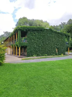 a building covered in ivy next to a green field at Lávka Park Skochovice in Vrané nad Vltavou
