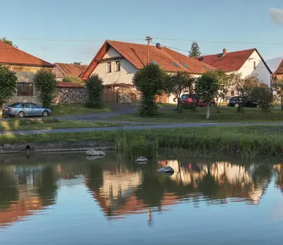 a pond in a village with houses and a car at Zelený statek in Bzová