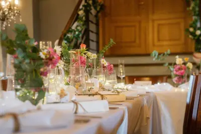 a table with white table cloth and vases with flowers at Pytloun Chateau Hotel Ctěnice in Prague